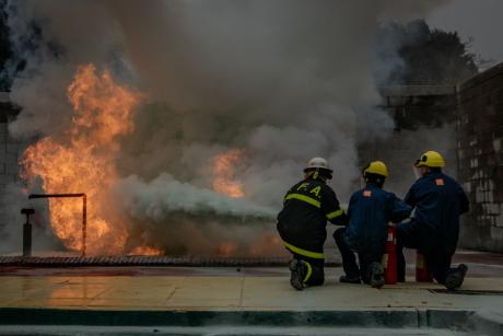 Brave firefighters practice extinguishing a controlled fire, showcasing teamwork and safety skills.