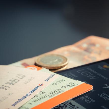 Airline ticket with euro coins and smartphone displaying flight details.