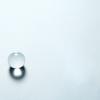 Minimalist composition with a transparent crystal sphere and cube casting shadows on a light background.