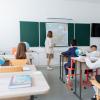 Students engaged in a geography lesson, focusing on a wall map in a classroom with globes and study materials.